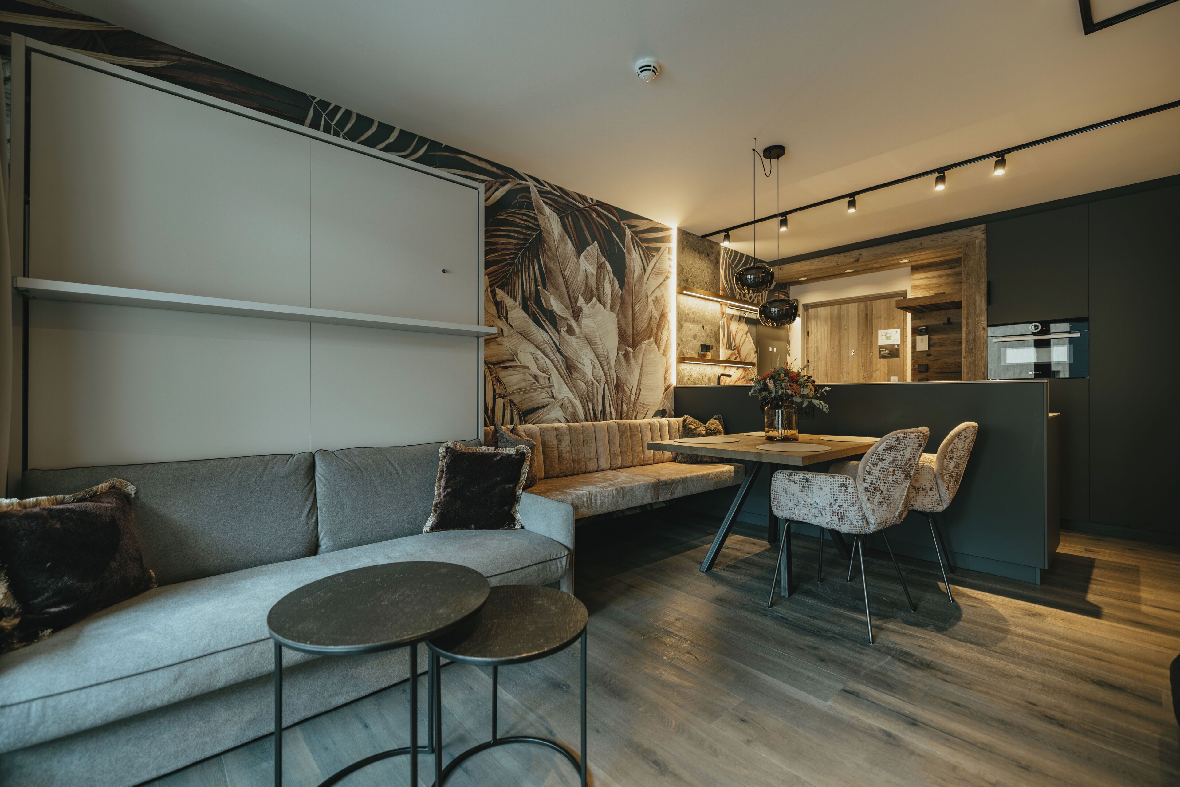 A modern living room with a sofa, a round table, and a dining area with chairs.