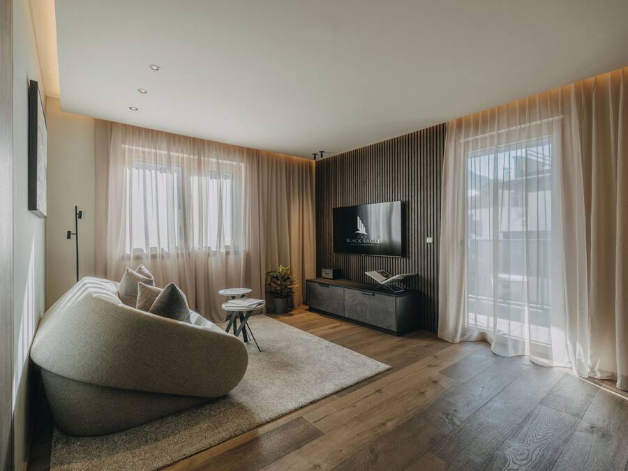 Una sala de estar moderna con un sofá, televisor y piso de madera.