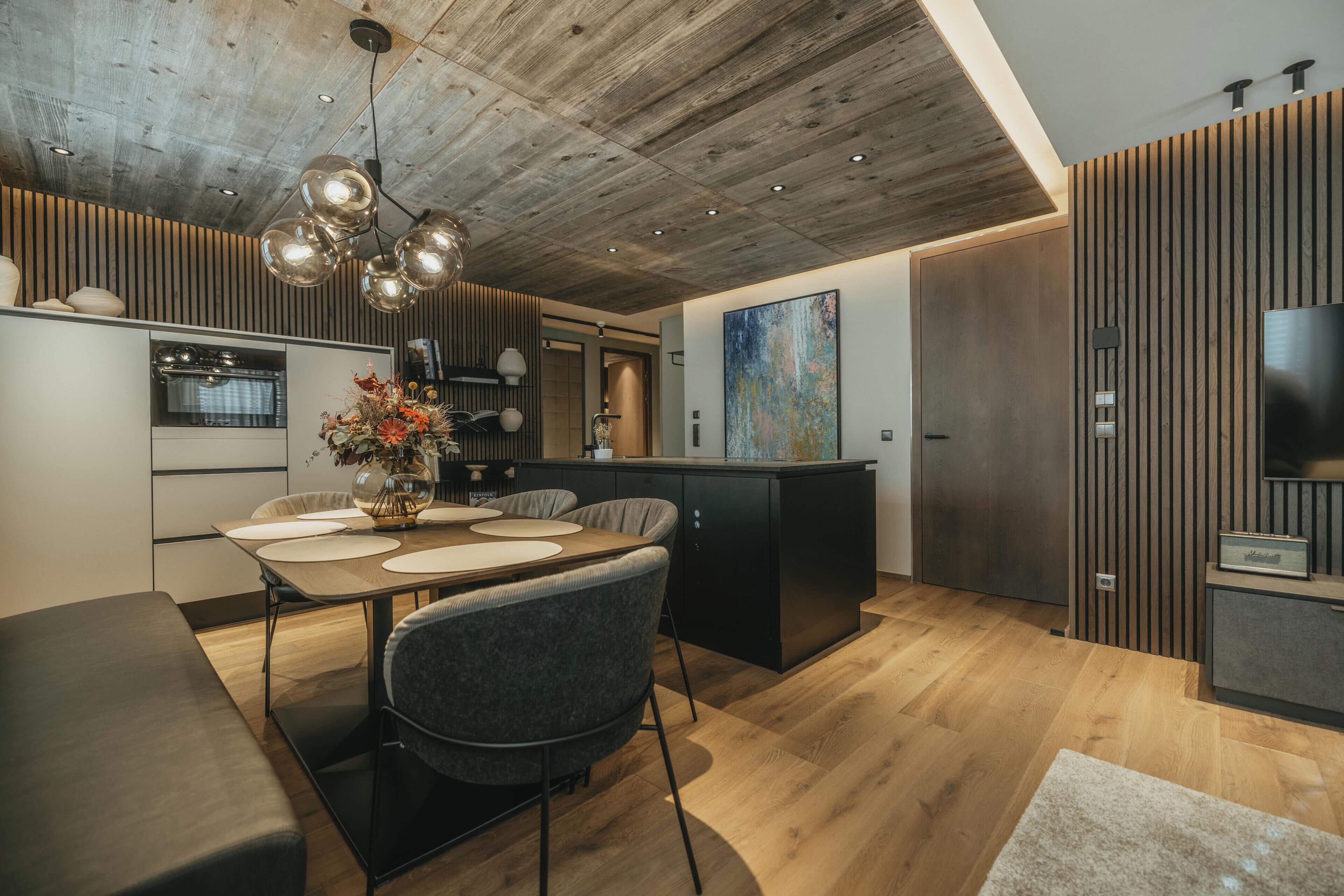 Una cocina moderna con una isla central, suelo de madera y un comedor con mesa y sillas.