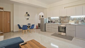 A modern kitchen with a dining area, featuring a refrigerator, oven, and tiled backsplash.
