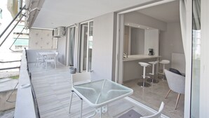 A modern, open-plan living area with a balcony, a kitchen, and a dining space.