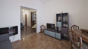 A modern living room with a flat-screen TV, a dining table, and a bookshelf. - Alemar Quiet Kallithea Retreat with AC, Wifi (Kalithea)