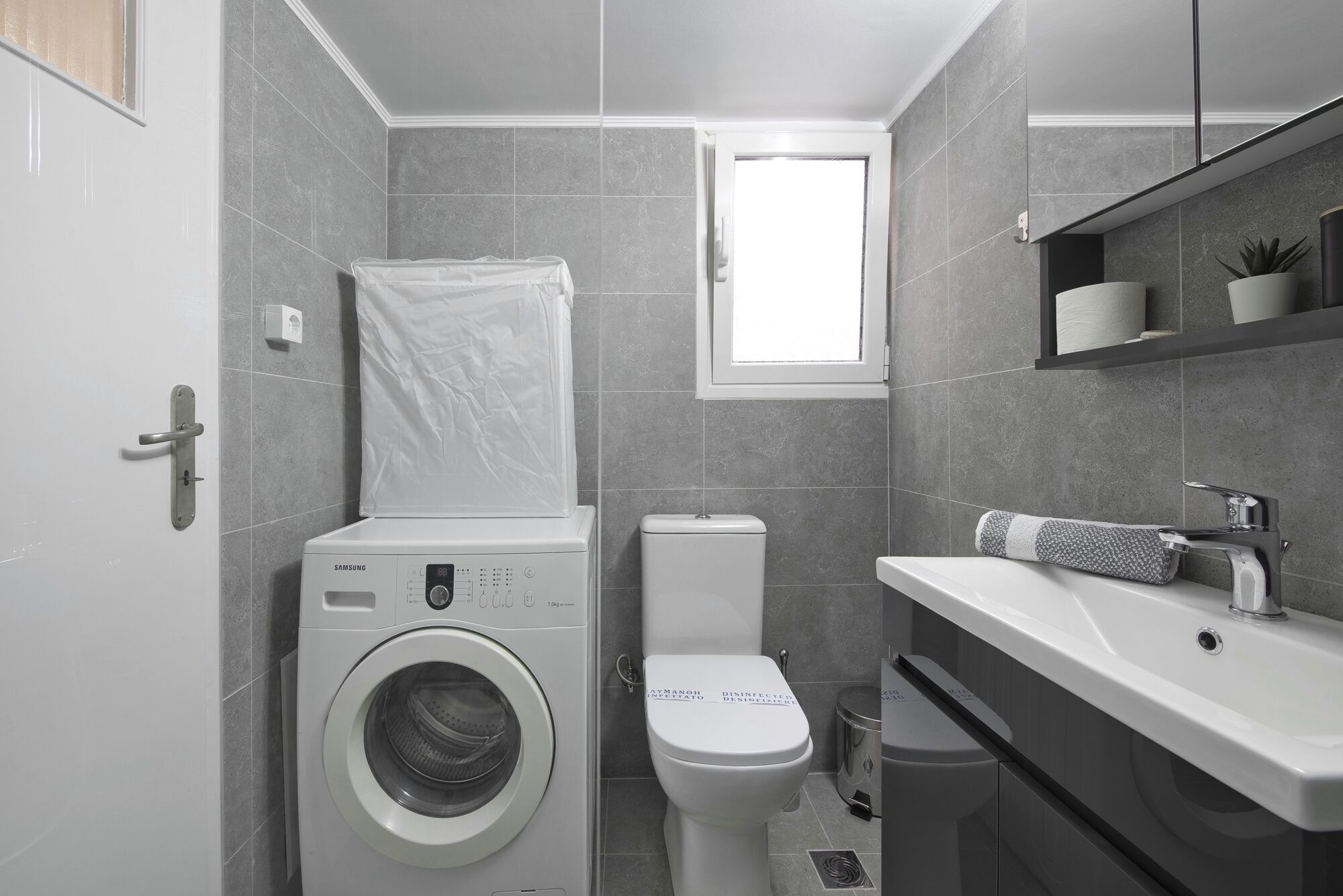 Un baño pequeño con lavadora, inodoro y lavamanos con toalla.