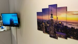 Une œuvre d’art représentant un paysage urbain au coucher du soleil, accrochée au mur.