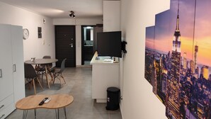 Une cuisine moderne avec un coin repas, un téléviseur fixé au mur et un grand tableau représentant un paysage urbain.