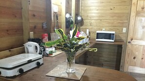 Een keuken met houten wanden, een magnetron, een koffiezetapparaat en een plant in een glazen vaas.
