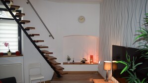 Ein modernes Wohnzimmer mit einer Holztreppe, einem Flachbildfernseher und einer Pflanze.