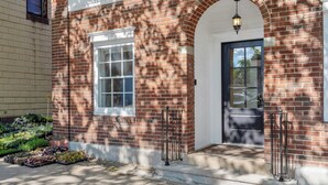 A brick building with a white door, a window, and a small porch area.