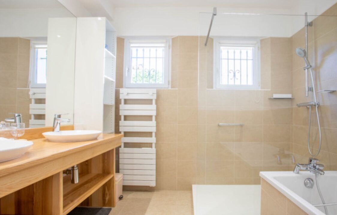 Ein modernes Badezimmer mit einer Badewanne, einer Dusche und einem Waschtisch mit zwei Becken.