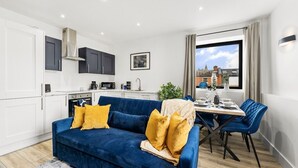 Ein gemütlicher Wohnbereich mit einem blauen Sofa, einem Esstisch und Stühlen.