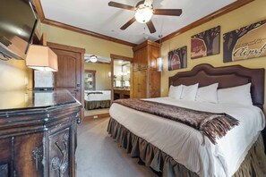 Un dormitorio con una cama grande, cabecera de madera, ventilador de techo y cómoda.