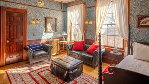 A room with a four-poster bed, two leather sofas, a wooden floor, patterned wallpaper, and a view through the window. - Hancock Historic Bed & Breakfast with Personal Chef Made-to-Order Full Breakfast (Hancock)