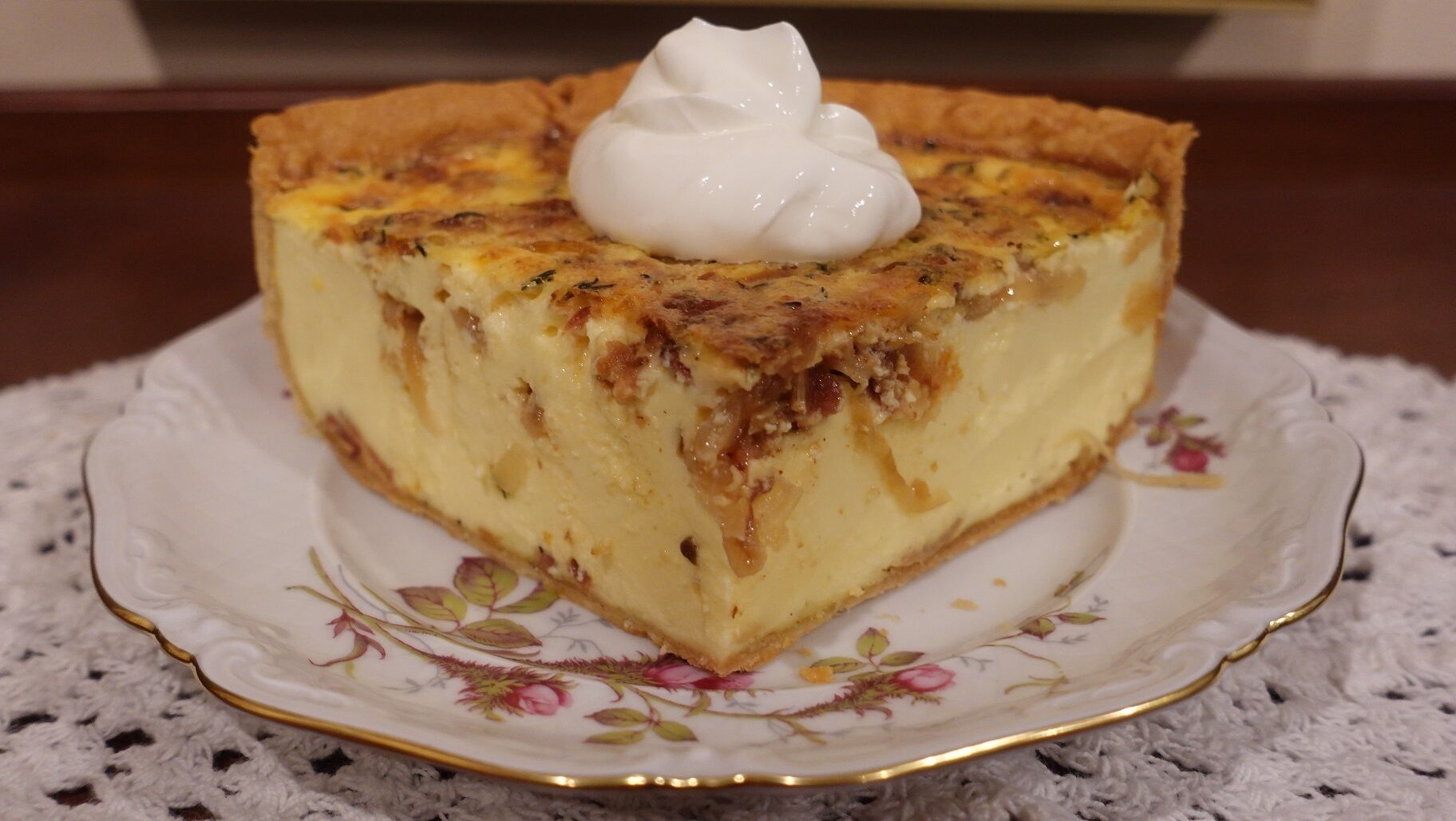 En skive quiche på en dekorativ tallerken.