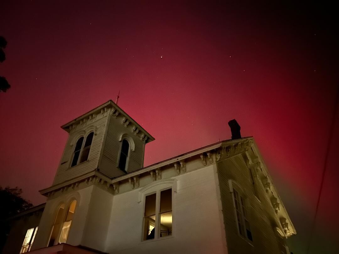 Un bâtiment doté d’une tour et de nombreuses fenêtres, sous un ciel nocturne où l’on peut voir des étoiles.