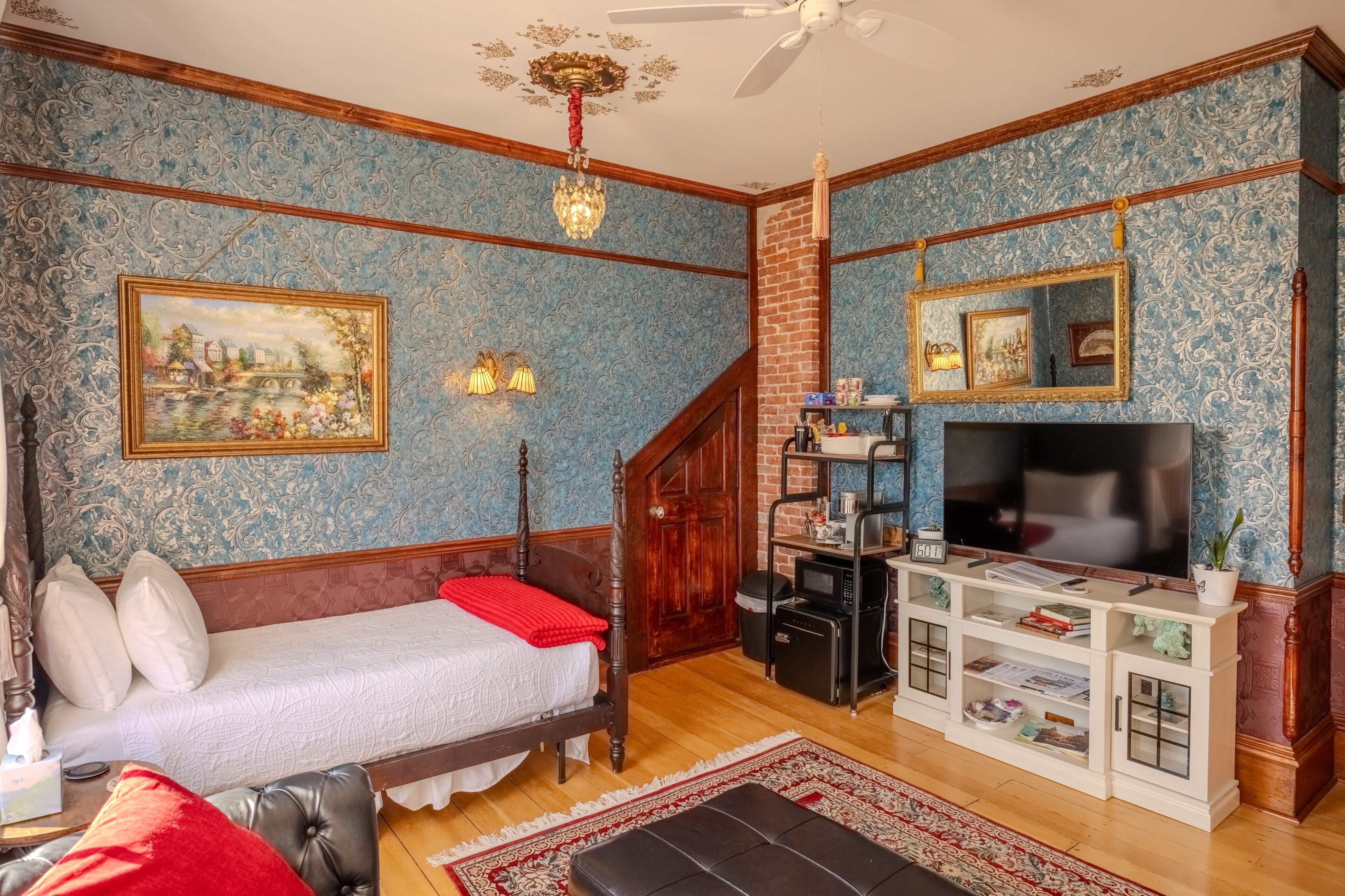 Una habitación con una cama, televisión, estantería y escalera.