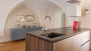 A modern kitchen with a central island, built-in cabinets, and an arched ceiling.