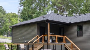 Une maison avec une terrasse en bois, un escalier et un garage.