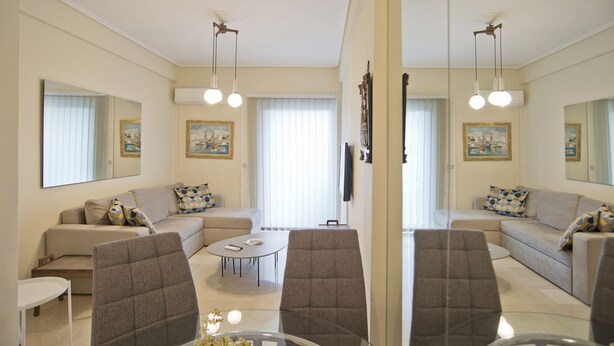 A modern living room with a sofa set, two armchairs, a coffee table, and a TV. - Riviera Living in Vouliagmeni (Vari-Voula-Vouliagmeni)