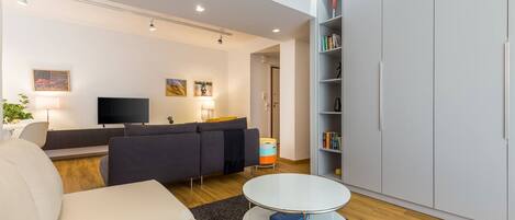 A modern living room with a sofa, a coffee table, a TV, and a bookshelf.