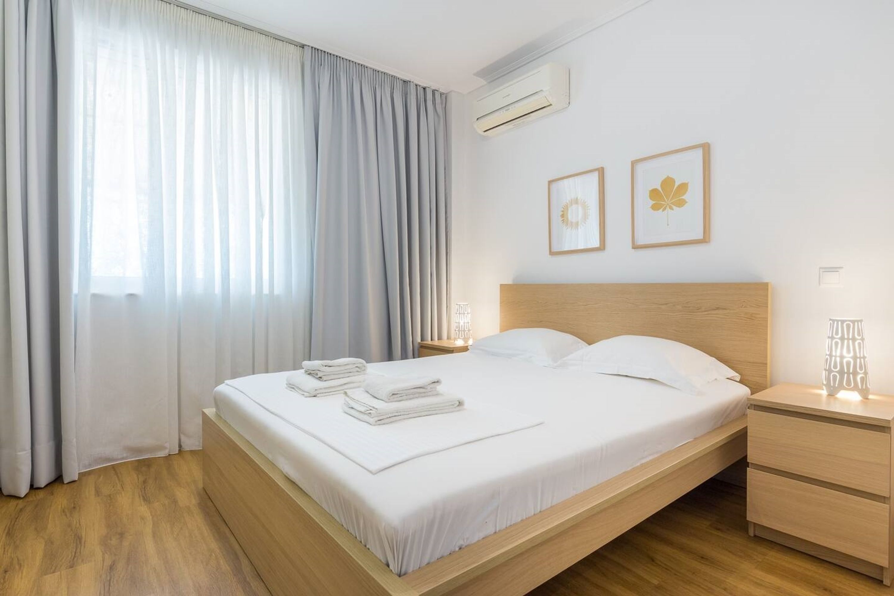 A neatly made bed with white linens, a wooden headboard, and a bedside table with a lamp.