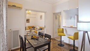 Een moderne eethoek met een tafel, stoelen en een radiator. Achtergrond is een bank en een fauteuil.