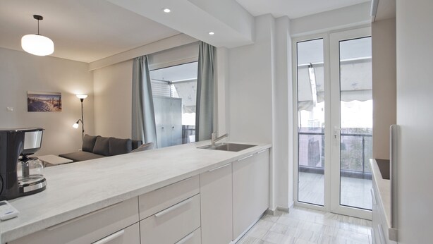 Et moderne køkken med en stor ø, indbygget ovn og et vindue med udsigt til en balkon.