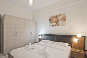 Ein modernes Hotelzimmer mit einem großen Bett, einem Schrank und einem Nachttisch mit Lampen.