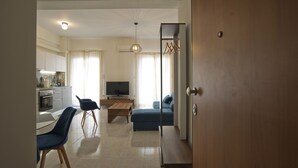 Ein modernes Wohnzimmer mit einer Couch, einem Fernseher und einem Essbereich mit Stühlen und einem Tisch.
