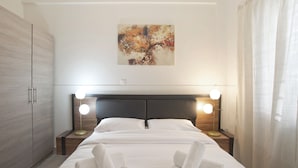 Ein ordentlich bezogenes Bett mit weißen Leinentüchern, zwei Nachttischlampen, einem Kopfteil und einem Bild an der Wand.