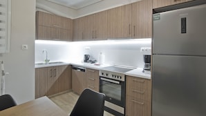 Eine moderne Küche mit Holzschränken, einem Edelstahlkühlschrank, einem Backofen und einem Geschirrspüler.
