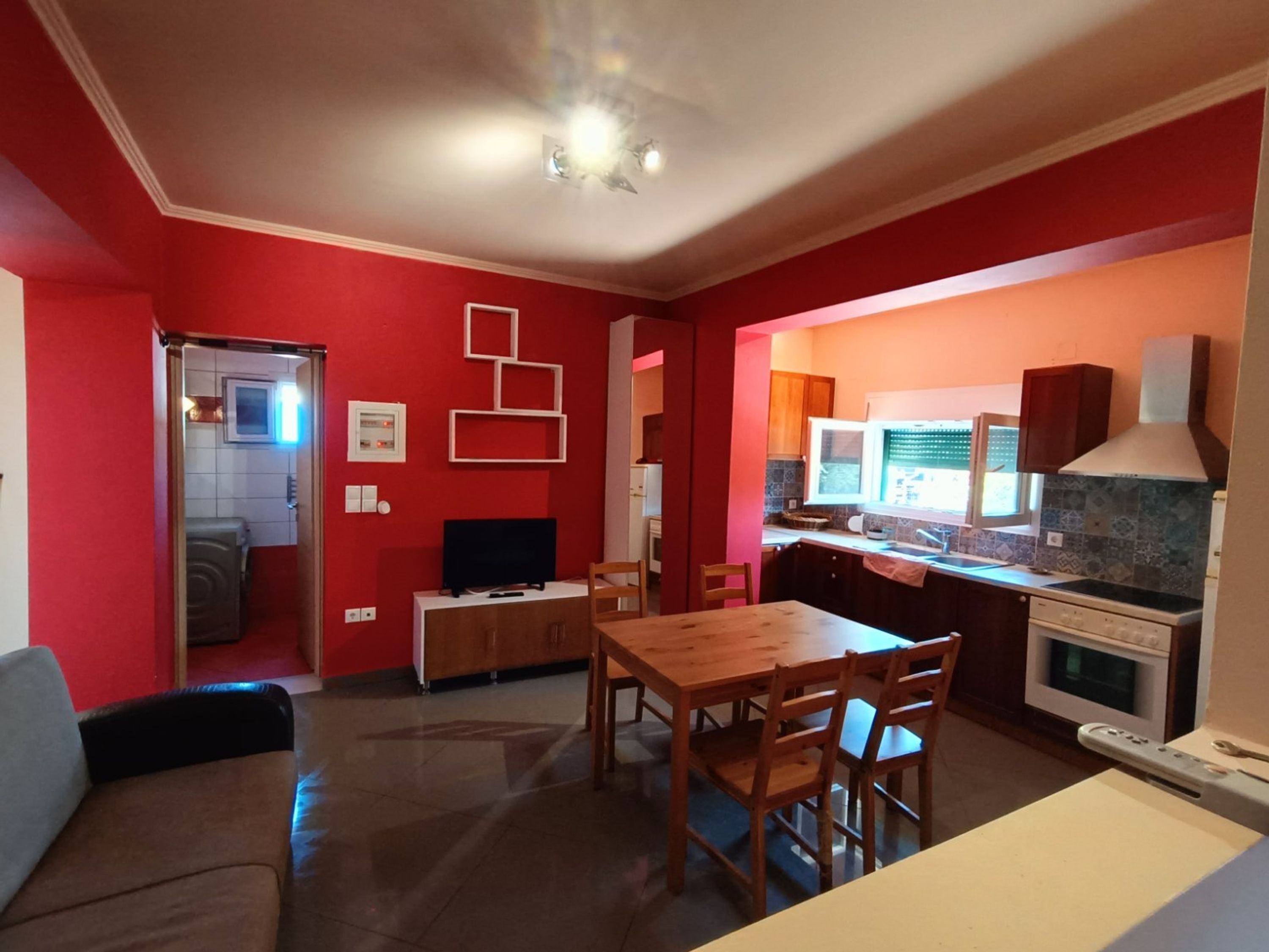 Un espace de vie compact comprenant un coin repas, une kitchenette et un téléviseur.