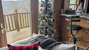 A cozy room with a wooden interior, a Christmas tree, and a view of the outdoors. - Dale Hollow Lakeview Getaway Log Cabin•3 Bedroom•2.5 Baths•Scenic View•Game Room (Byrdstown)