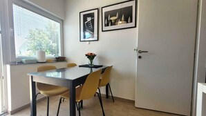 Ein Essbereich mit Tisch, Stühlen, einem Blumenstrauß und zwei gerahmten Bildern an der Wand.