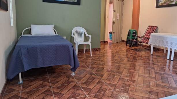 Een kamer met een bed, een stoel, een tafel en een deur naar een andere kamer.