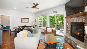 Una sala de estar moderna con chimenea, ventilador de techo y comedor con mesa y sillas.