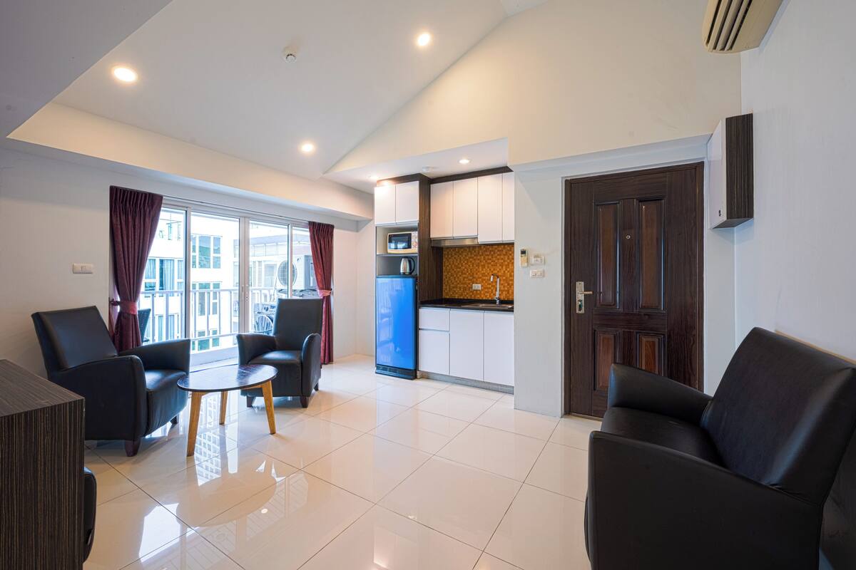 Una sala de estar moderna con comedor, cocina y un amplio ventanal con cortinas.