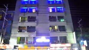 A multi-story building with illuminated windows and balconies, featuring a prominent sign at the ground level. - Ocean Palace Cox'sBazar (Cox's Bazar)