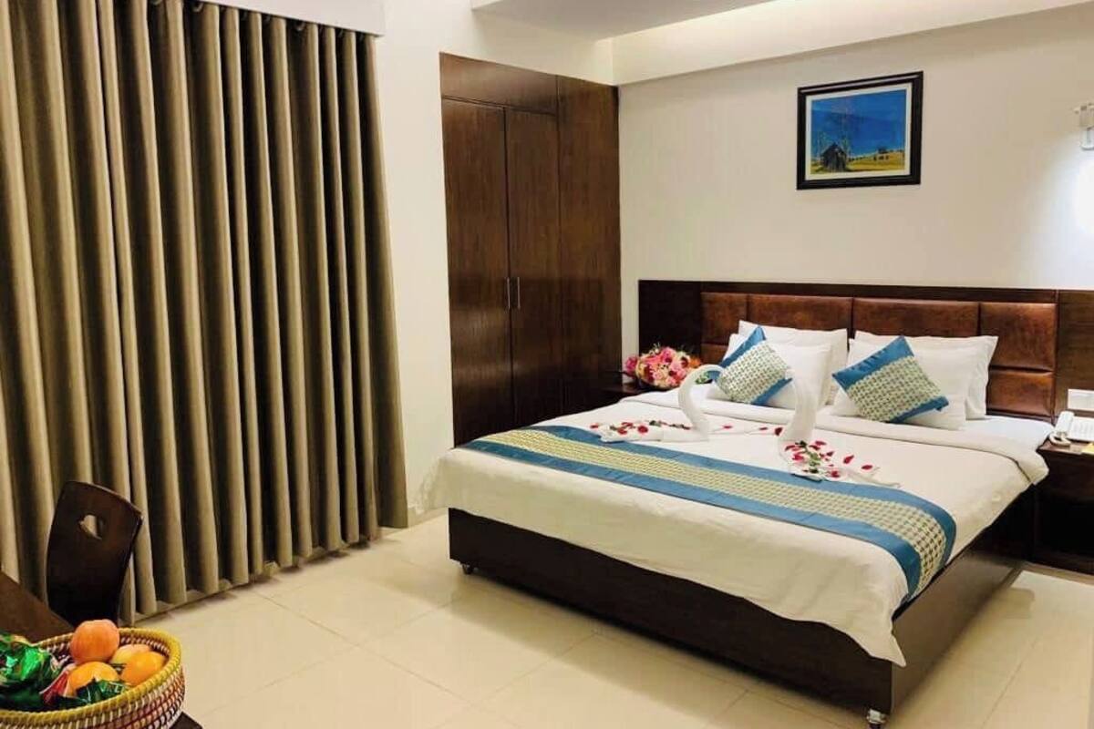 A neatly arranged bedroom with a bed, a nightstand, a wooden wardrobe, and a wall-mounted picture.