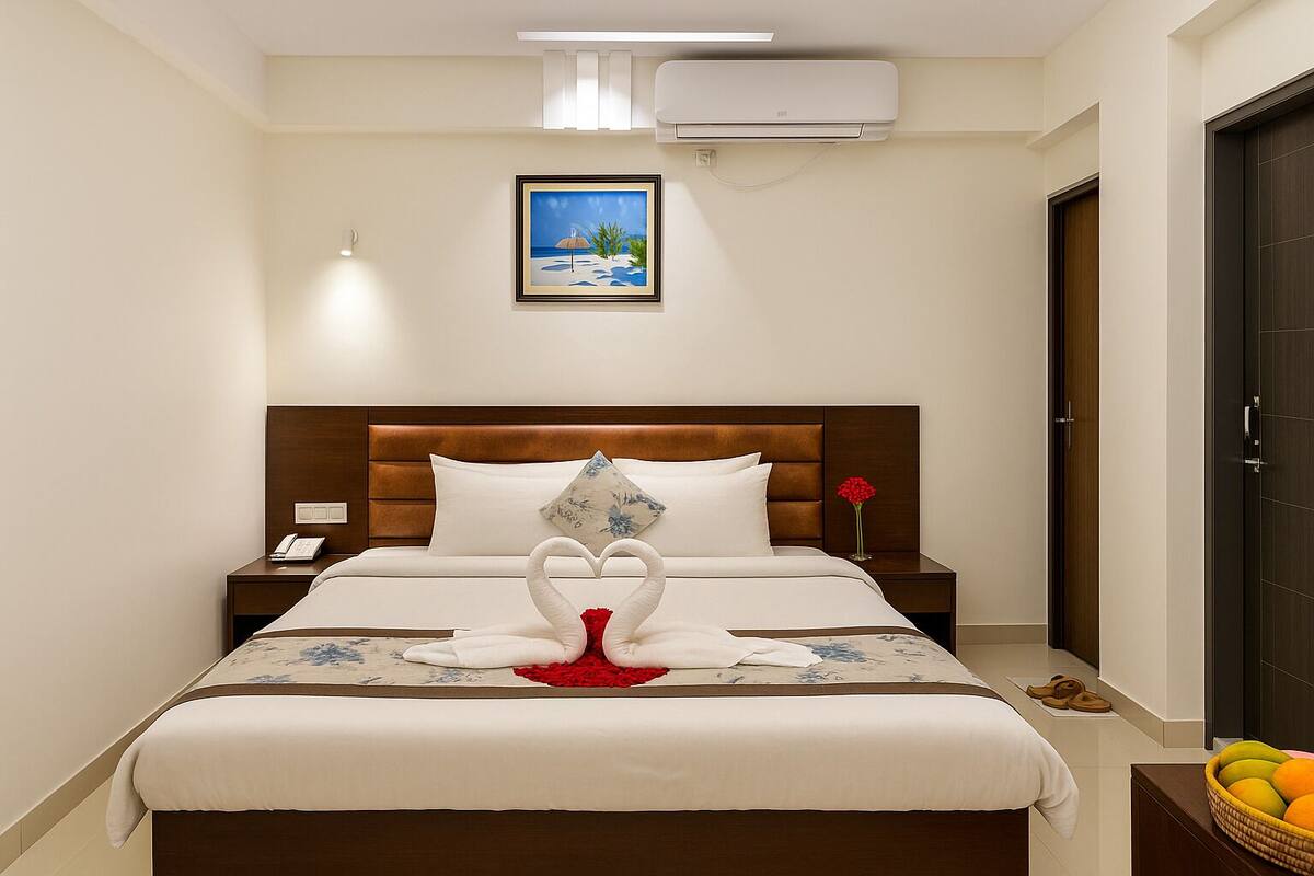 A neatly arranged hotel room with a bed, bedside tables, a wall-mounted air conditioner, and a framed picture above the bed.