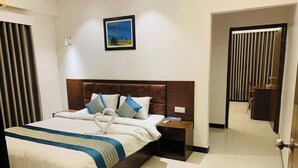 A hotel room with a large bed, a nightstand, a wall-mounted picture, and a door leading to another room. - Ocean Palace Cox'sBazar (Cox's Bazar)