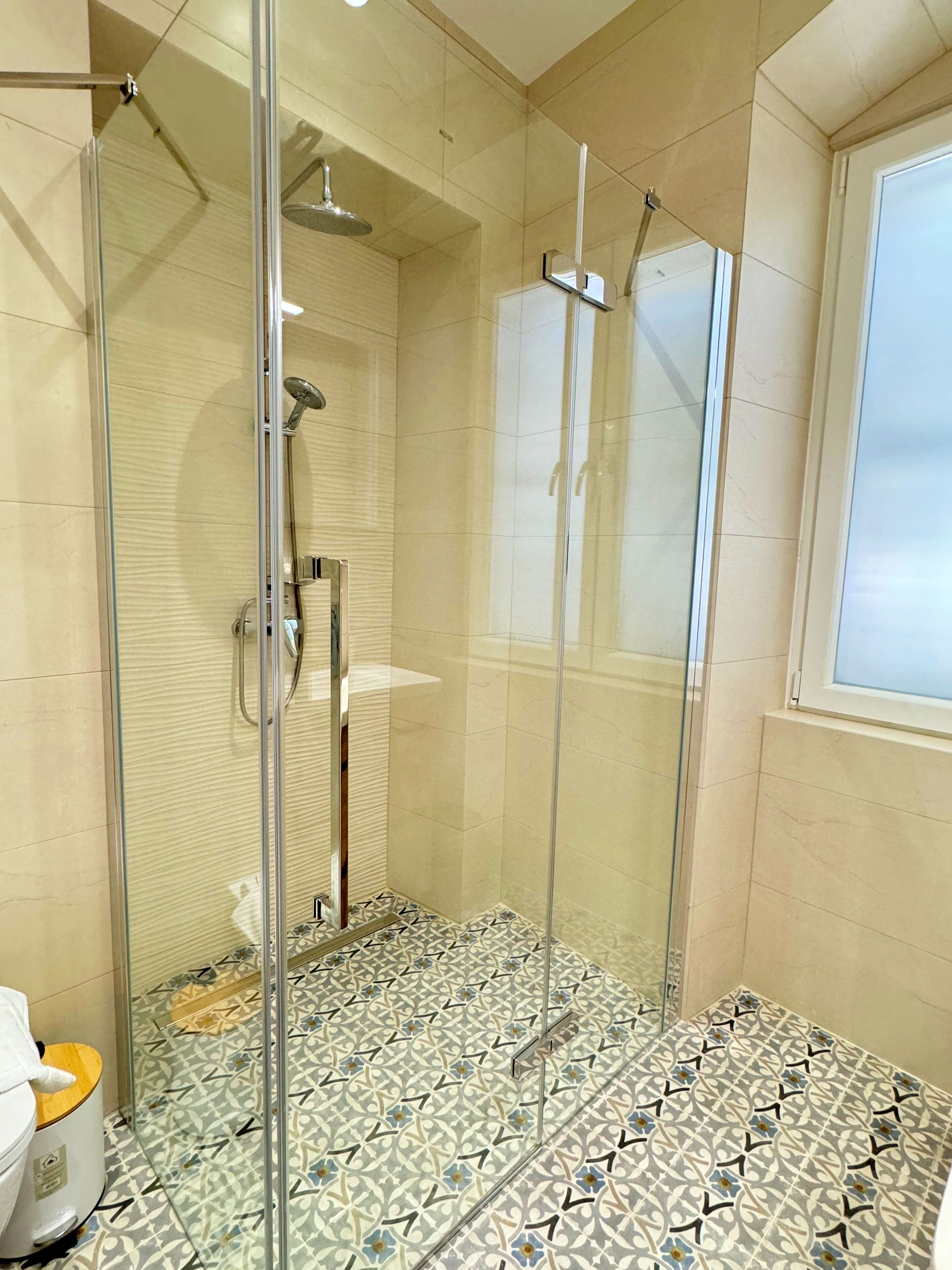 A modern bathroom with a glass-enclosed shower, a toilet, and a sink.