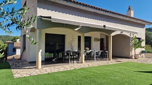 A house with a covered patio area, a stone pathway, and a well-maintained lawn.