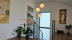 A staircase with a metal railing, potted plants, and artwork on the walls.