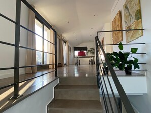 A modern interior with a staircase, a dining area, and a kitchen in the background.