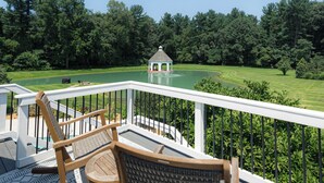 Eine Terrasse mit einem Pavillon im Hintergrund, umgeben von einer gepflegten Rasenfläche und Bäumen.