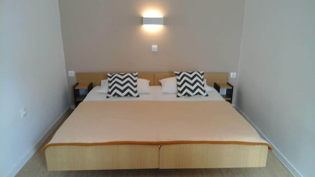 Ein Doppelbett mit Holz-Kopfteil, zwei Nachttische und zwei Kissen mit Schwarz-Weiß-Muster.