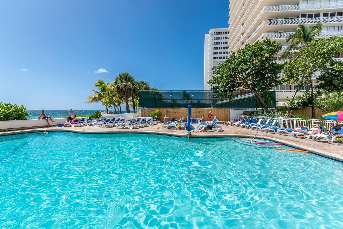 Área da piscina com espreguiçadeiras e vista para o oceano.