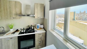 Una cuina moderna amb armaris de fusta, una placa de cocció, un rentaplat i una finestra amb vista a la ciutat.
