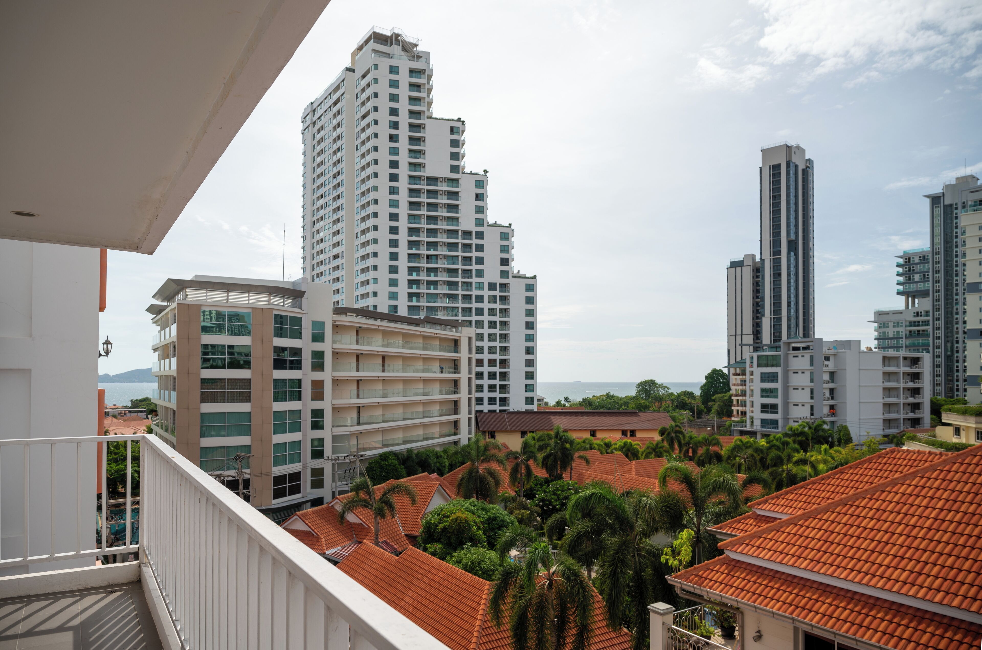 Un immeuble de grande hauteur doté de nombreux balcons, entouré de palmiers et d’autres plantes vertes.