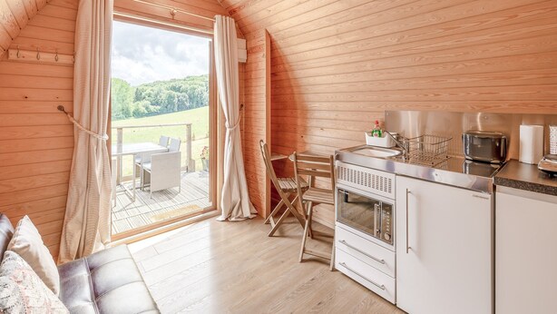 A cozy, wooden interior with a dining area, a kitchen, and a view of a green landscape. - 1 bedroom accommodation in Ross-on-Wye (Ross-on-Wye)
